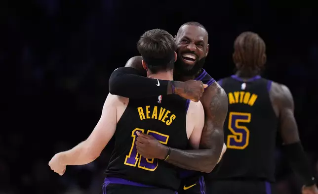 Los Angeles Lakers guard Austin Reaves (15) is embraced by forward LeBron James after Reaves made a three-point basket during the first half of an NBA basketball game against the Utah Jazz Tuesday, Nov. 18, 2025, in Los Angeles. (AP Photo/Jae C. Hong)