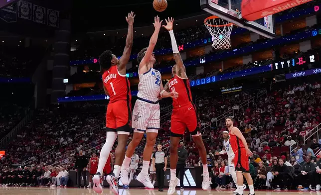 Orlando Magic forward Franz Wagner (22) shoots against Houston Rockets guard Amen Thompson (1) and forward Jabari Smith Jr. (10) during the first half of an NBA basketball game in Houston, Sunday, Nov. 16, 2025. (AP Photo/Ashley Landis)
