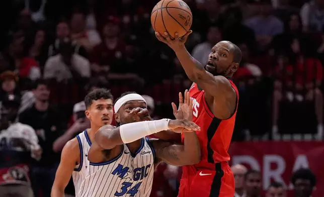 Orlando Magic center Wendell Carter Jr. (34) and Houston Rockets forward Kevin Durant (7) reach for a loose ball during the first half of an NBA basketball game in Houston, Sunday, Nov. 16, 2025. (AP Photo/Ashley Landis)