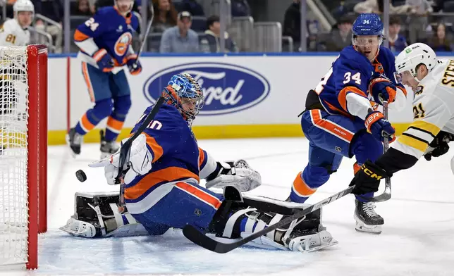 Boston Bruins center Alex Steeves, right, scores a goal past New York Islanders goaltender Ilya Sorokin in the first period of an NHL hockey game, Wednesday, Nov. 26, 2025, in Elmont, N.Y. (AP Photo/Adam Hunger)