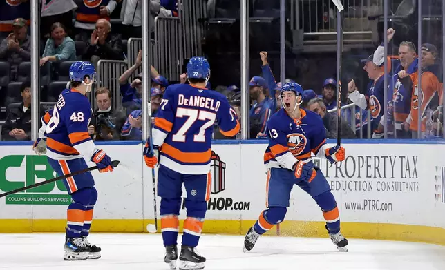 New York Islanders center Mathew Barzal, right, celebrates scoring a goal with defenseman Tony Deangelo (77) and defenseman Matthew Schaefer (48) in the first period of an NHL hockey game against the Boston Bruins, Wednesday, Nov. 26, 2025, in Elmont, N.Y. (AP Photo/Adam Hunger)
