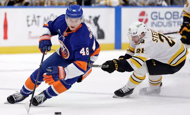 New York Islanders defenseman Matthew Schaefer (48) controls the puck past Boston Bruins center Alex Steeves (21) in the first period of an NHL hockey game, Wednesday, Nov. 26, 2025, in Elmont, N.Y. (AP Photo/Adam Hunger)