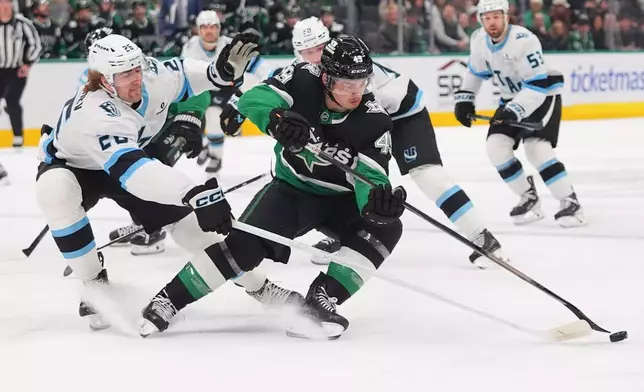 Dallas Stars center Justin Hryckowian (49) and Utah Mammoth defenseman Dmitri Simashev (26) skate for the puck during the first period of an NHL hockey game Friday, Nov. 28, 2025, in Dallas. (AP Photo/LM Otero)