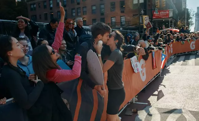 A runner takes a break to kiss her partner during the New York City Marathon in New York, Sunday, Nov. 2, 2025. (AP Photo/Andres Kudacki)