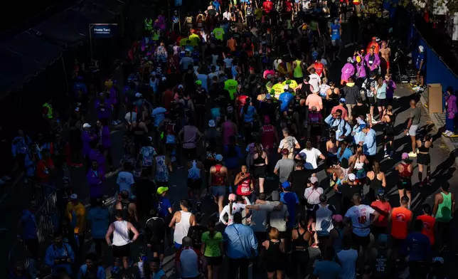 People walk and take photos after crossing the finish line of the New York City Marathon, Sunday, Nov. 2, 2025, in New York. (AP Photo/Angelina Katsanis)