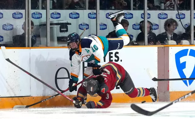 New York Sirens' Sarah Fillier (10) falls on top of Ottawa Charge's Jocelyne Larocque (3) as they battle for the puck during the second period of a PWHL hockey game in Ottawa, Ontario, Saturday, Nov. 22, 2025. (Justin Tang/The Canadian Press via AP)