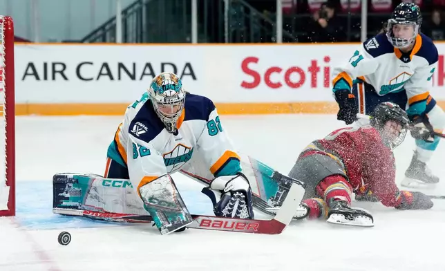 New York Sirens goaltender Kayle Osborne (82) watches the puck as Ottawa Charge's Brianne Jenner (19) slides along the ice, during first period PWHL hockey action in Ottawa, on Saturday, Nov. 22, 2025. (Justin Tang/The Canadian Press via AP)