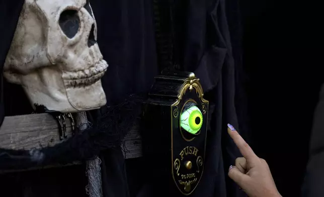 A girl rings the doorbell of a horror-themed room at the West Side Hallo Fest, the country's largest Halloween festival in Bucharest, Romania, Friday, Oct. 24, 2025. (AP Photo/Andreea Alexandru)