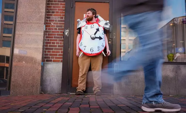 Pharmacy manager Tyler O'Neil wears an alarm clock costume while taking a work break, Friday, Oct. 31, 2025, in Portland, Maine. (AP Photo/Robert F. Bukaty)