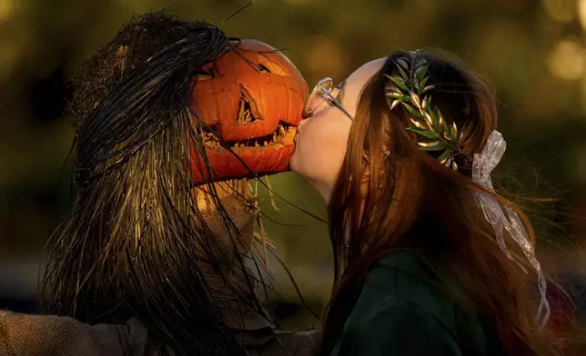 A girl poses for a friend while kissing a pumpkin at the West Side Hallo Fest, the country's largest Halloween festival in Bucharest, Romania, Friday, Oct. 24, 2025. (AP Photo/Andreea Alexandru)