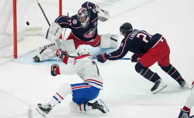 Columbus Blue Jackets goaltender Jet Greaves (73) blocks a shot by Montreal Canadiens center Jake Evans (71) as center Isac Lundestrom moves in to assist in the first period of an NHL hockey game in Columbus, Monday, Nov. 17, 2025. (AP Photo/Sue Ogrocki)