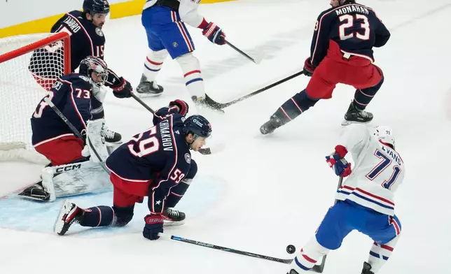 Columbus Blue Jackets right wing Yegor Chinakhov (59) blocks a shot by Montreal Canadiens center Jake Evans (71) in front of goaltender Jet Greaves (73) in the first period of an NHL hockey game in Columbus, Monday, Nov. 17, 2025. (AP Photo/Sue Ogrocki)