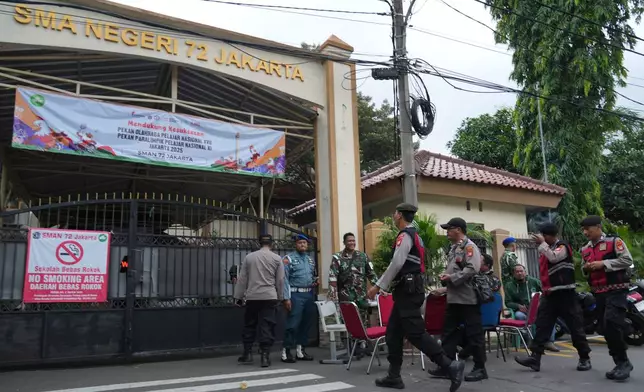 Police officers and military personnel stand guard at the gate of a school after explosions in Jakarta, Indonesia, Saturday, Nov. 8, 2025. (AP Photo/Achmad Ibrahim)