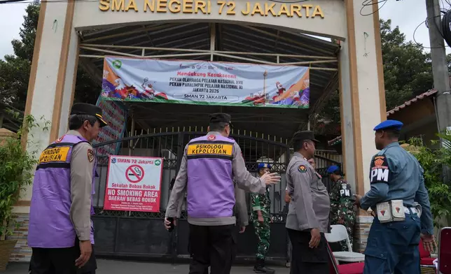 Police officers and military personnel stand guard at the gate of a school after explosions in Jakarta, Indonesia, Saturday, Nov. 8, 2025. (AP Photo/Achmad Ibrahim)