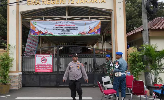 Police officers and military personnel stand guard at the gate of a school after explosions in Jakarta, Indonesia, Saturday, Nov. 8, 2025. (AP Photo/Achmad Ibrahim)