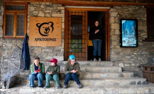 Visitors sit on the stairs inside the Arcturos bear sanctuary in Nymfaio, northern Greece, on Thursday, Oct. 30, 2025. (AP Photo/Giannis Papanikos)