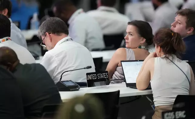 Delegates surround an empty spot where the placard for the United States sits at the COP30 U.N. Climate Summit, Saturday, Nov. 22, 2025, in Belem, Brazil. (AP Photo/Fernando Llano)