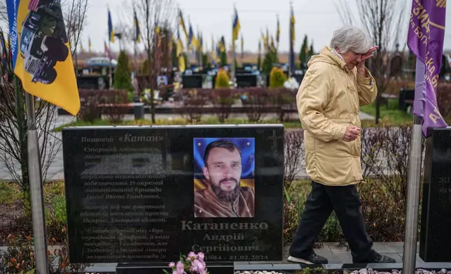 Vira Katanenko, 66, cries while visiting a grave of her son Andrii Katanenko, a Ukrainian serviceman of 59th brigade at the cemetery in Bucha, Ukraine, on Sunday, Nov. 23, 2025. (AP Photo/Evgeniy Maloletka)