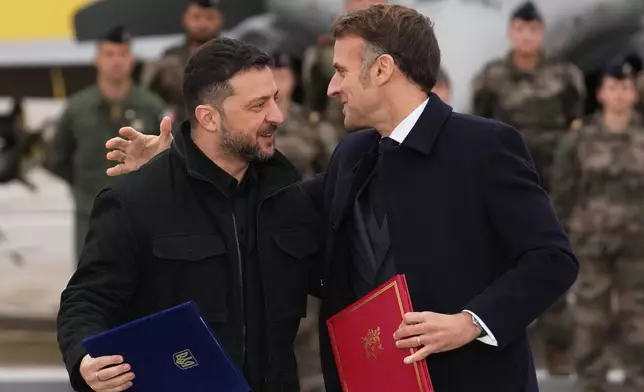 French President Emmanuel Macron, right, and Ukrainian President Volodymyr Zelenskyy hug after signing an agreement Monday, Nov. 17, 2025 at the Villacoublay air base near Paris. (AP Photo/Christophe Ena, Pool)