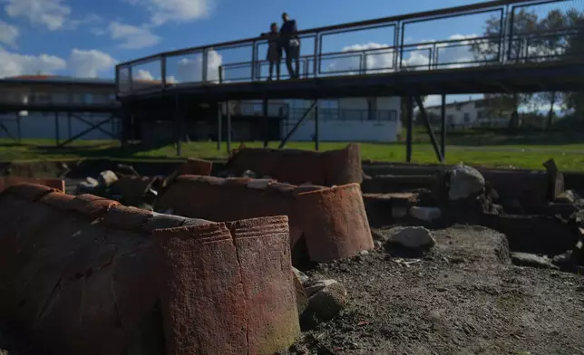 Visitors look at tombs at archaeological excavations of the ancient Byzantine-era Christian Saint Neophytos Basilica, in Iznik, also known by its ancient name Nicaea, northwestern Turkey, Thursday, Nov. 13, 2025, ahead of the visit of Pope Leo XIV to mark the 1,700th anniversary of the First Council of Nicaea. (AP Photo/Francisco Seco)