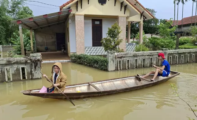 Local residents paddle a boat through a flooded street in Hue, Vietnam, Friday, Oct. 31, 2025. (Mai Huyen Trang/VNA via AP)
