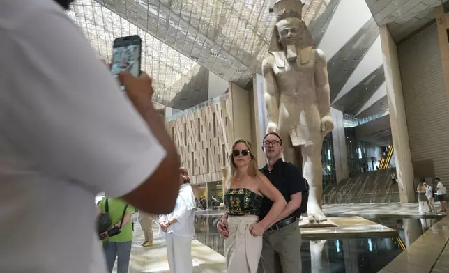 Tourists pose for a picture in front of the statue of Pharaoh Ramses II, at the Grand Egyptian Museum in Giza, Egypt, Friday, May 23, 2025. (AP Photo/Amr Nabil)