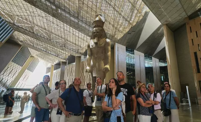 Tourists stand under the statue of Pharaoh Ramses II, at the Grand Egyptian Museum in Giza, Egypt, Friday, May 23, 2025. (AP Photo/Amr Nabil)