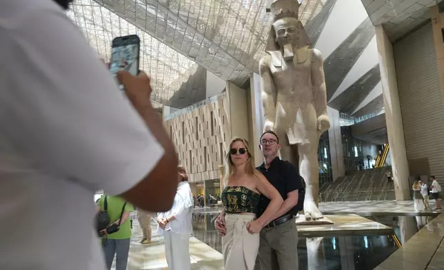 Tourists pose for a picture in front of the statue of Pharaoh Ramses II, at the Grand Egyptian Museum in Giza, Egypt, Friday, May 23, 2025. (AP Photo/Amr Nabil)