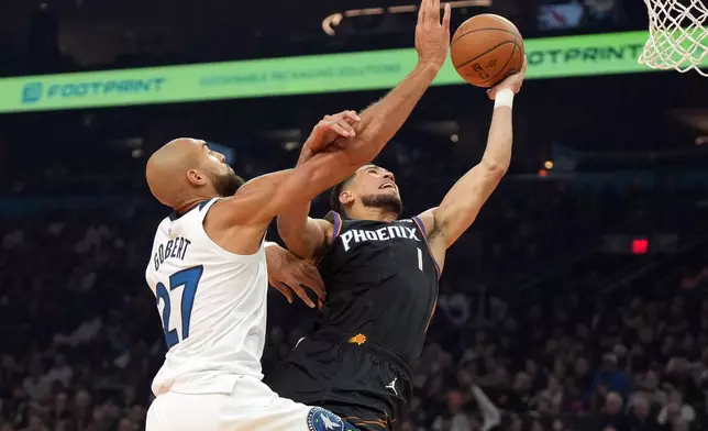 Phoenix Suns guard Devin Booker, right, drives past Minnesota Timberwolves center Rudy Gobert (27) during the first half of an NBA Cup basketball game, Friday, Nov. 21, 2025, in Phoenix. (AP Photo/Rick Scuteri)