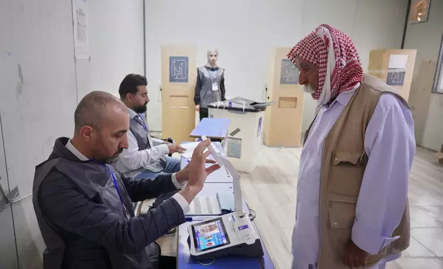 A displaced Yazidi man has his fingerprint verified before voting ahead of Iraq's parliamentary elections, set for Nov. 11, at a polling station in the Sharia camp near Dohuk, in Iraq's semi-autonomous Kurdish region, Sunday, Nov. 9, 2025. (AP Photo/Rashid Yahya)