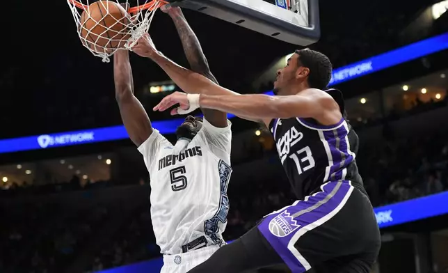 Memphis Grizzlies guard Vince Williams Jr. (5) dunks against Sacramento Kings forward Keegan Murray (13) in the first half of an NBA basketball game Thursday, Nov. 20, 2025, in Memphis, Tenn. (AP Photo/Brandon Dill)