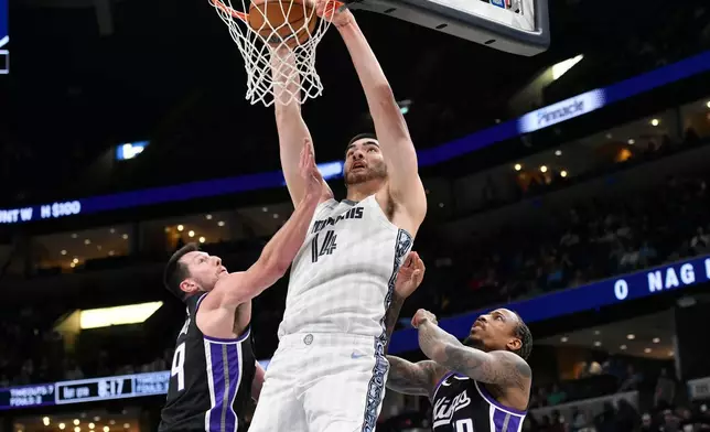 Memphis Grizzlies center Zach Edey (14) dunks over Sacramento Kings forward Drew Eubanks (19) and guard DeMar DeRozan (10) in the first half of an NBA basketball game, Thursday, Nov. 20, 2025, in Memphis, Tenn. (AP Photo/Brandon Dill)