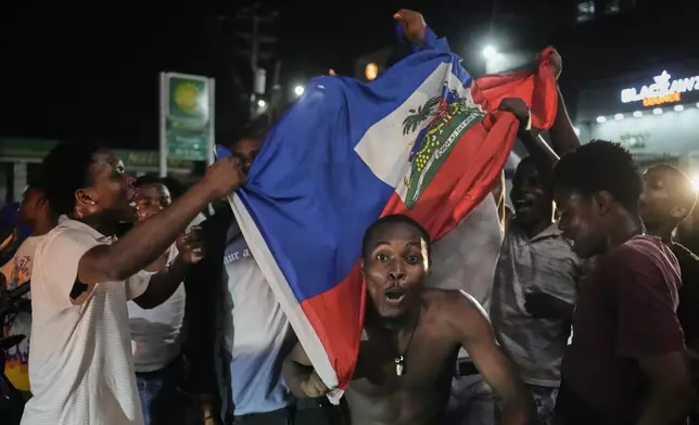 Fans celebrate Haiti's qualification for the 2026 FIFA World Cup after a soccer match against Nicaragua, in Port-au-Prince, Haiti, Tuesday, Nov. 18, 2025. (AP Photo/Odelyn Joseph)