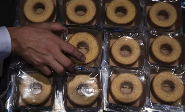 A vendor sorts articles at a baumkuchen store on its opening day in Tokyo, Friday, July 18, 2025. (AP Photo/Louise Delmotte)