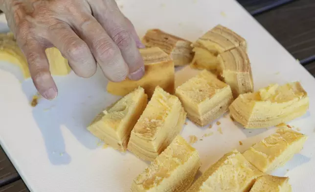 Staff and participants try out baked Baumkuchen, a German layered cake, during a workshop of Juchheim Ninoshima Welcome Center and Outdoor Activity Camp Monday, July 7, 2025, at Ninoshima island in Hiroshima, western Japan. (AP Photo/Eugene Hoshiko)