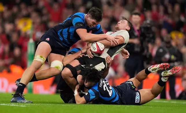 Japan's Harry Hockings, left, and Wales' Alex Mann, center, battle for the ball during the rugby union Nations Series match between Wales and Japan at the Principality Stadium, Cardiff, Saturday, Nov. 15, 2025. (Andrew Matthews/PA via AP)