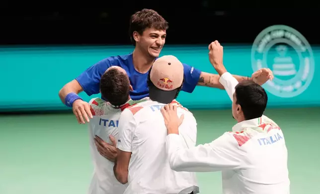 Italy's Flavio Cobolli, top, celebrates with teammates after winning a Davis Cup final singles tennis match against Spain's Jaume Munar, in Bologna, Italy, Sunday, Nov. 23, 2025. (AP Photo/Luca Bruno)