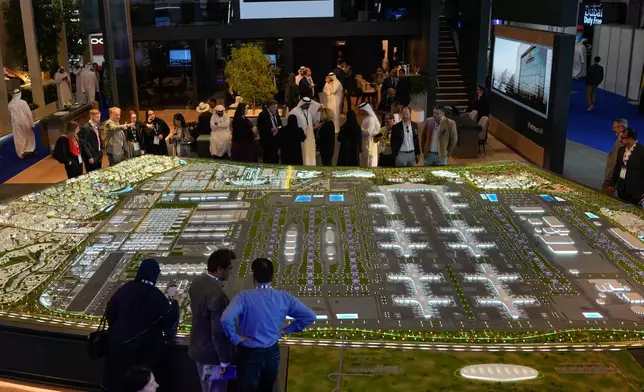 Visitors gather around a model of a $35 billion five-runway airport at Al Maktoum International Airport project, during the Dubai Air Show, United Arab Emirates, Wednesday, Nov. 19, 2025. (AP Photo/Altaf Qadri)