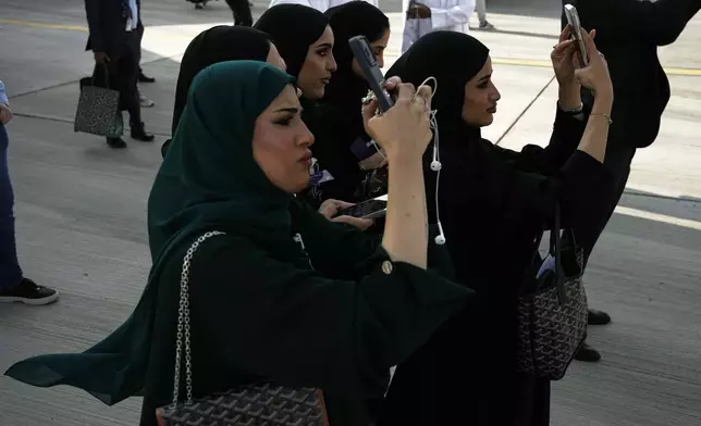 Emirati women take photos as planes perform during the Dubai Air Show in Dubai, United Arab Emirates, Tuesday, Nov. 18, 2025. (AP Photo/Fatima Shbair)
