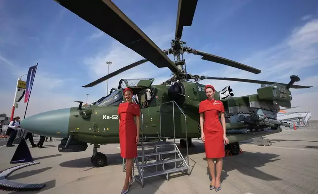 FILE - Russian hostesses stand by a Russian KA-52 attack helicopter at the Dubai Air Show in Dubai, United Arab Emirates, Nov. 17, 2025. (AP Photo/ Fatima Shbair, File)