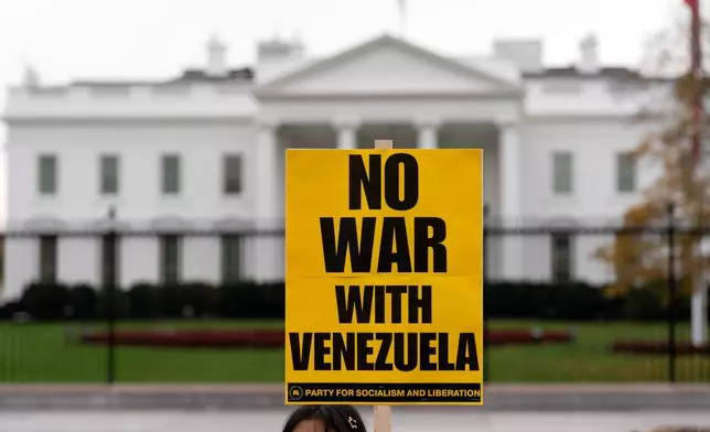 A demonstrator holds a sign while protesting outside of the White House in Washington, Saturday, Nov. 15, 2025. (AP Photo/Jose Luis Magana)