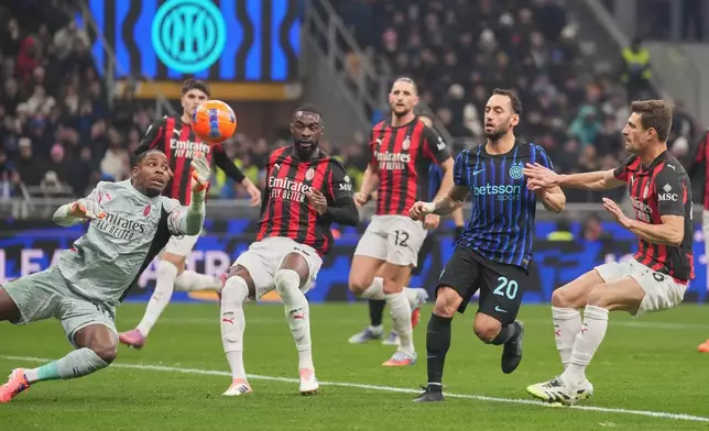 AC Milan's goalkeeper Mike Maignan saves in front of Inter Milan's Hakan Calhanoglu during the Serie A soccer match between Inter Milan and AC Milan in Milan, Italy, Sunday, Nov. 23, 2025. (AP Photo/Antonio Calanni)