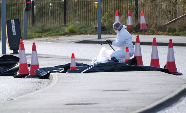 A forensic investigator works on a road leading to a train station after a mass stabbing on a London-bound train in Huntingdon, England, Sunday, Nov. 2, 2025.(AP Photo/Kirsty Wigglesworth)