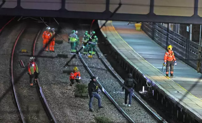 Emergency responders on the tracks by the train at Huntingdon station after a mass stabbing on a London-bound train in eastern England, in Cambridgeshire, England, Saturday, Nov. 1, 2025. (Chris Radburn/PA via AP)
