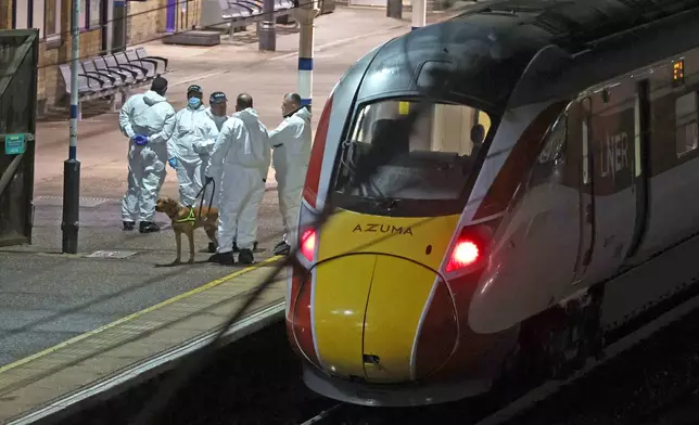 Forensic investigators on the platform by a train at Huntingdon station after a mass stabbing on a London-bound train in eastern England, in Cambridgeshire, England, Saturday, Nov. 1, 2025. (Chris Radburn/PA via AP)