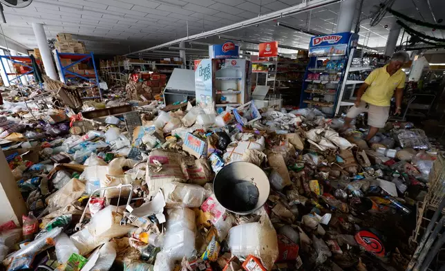 Somsak Remsringam, owner of the convenience shop, looks at the damaged contents after floods in Songkhla province, southern Thailand, Friday, Nov. 28, 2025. (AP Photo/Sarot Meksophawannakul)