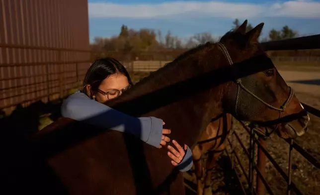 Sydney Diaz-Corral embraces a horse during a class in the Nueta Hidatsa Sahnish College equine studies program at the Healing Horse Ranch, Wednesday, Oct. 29, 2025, in Parshall, N.D. (AP Photo/John Locher)