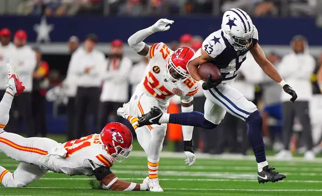 Dallas Cowboys running back Malik Davis, right, scores on a touchdown run past Kansas City Chiefs defensive back Chamarri Conner (27) and defensive back Jaden Hicks (21) during the first half of an NFL football game Thursday, Nov. 27, 2025, in Arlington, Texas. (AP Photo/LM Otero)