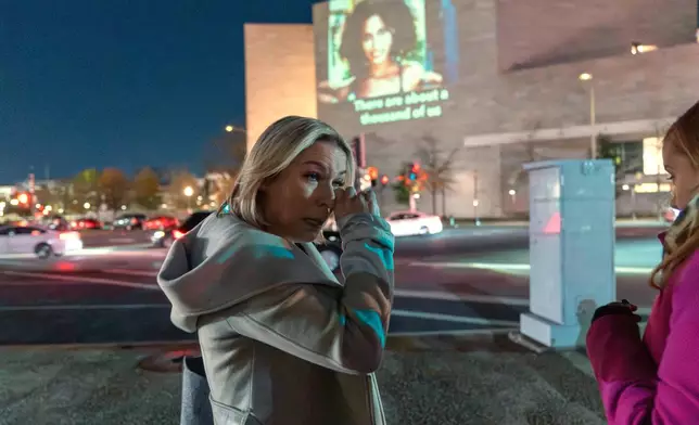 Danielle Bensky wipes a tear as a World Without Exploitation projection is seen on the wall of the National Gallery of Art calling on Congress to vote yes on the Epstein files transparency act in Washington, Monday, Nov. 17, 2025. (AP Photo/Jose Luis Magana)
