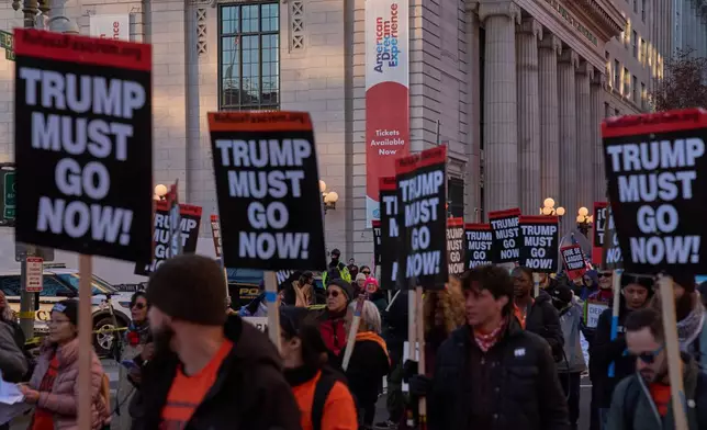Protesters march past the Milken Center for Advancing the American Dream, during a "Trump Must Go Now!" rally by the White House, Monday, Nov. 17, 2025, in Washington. (AP Photo/Jacquelyn Martin)